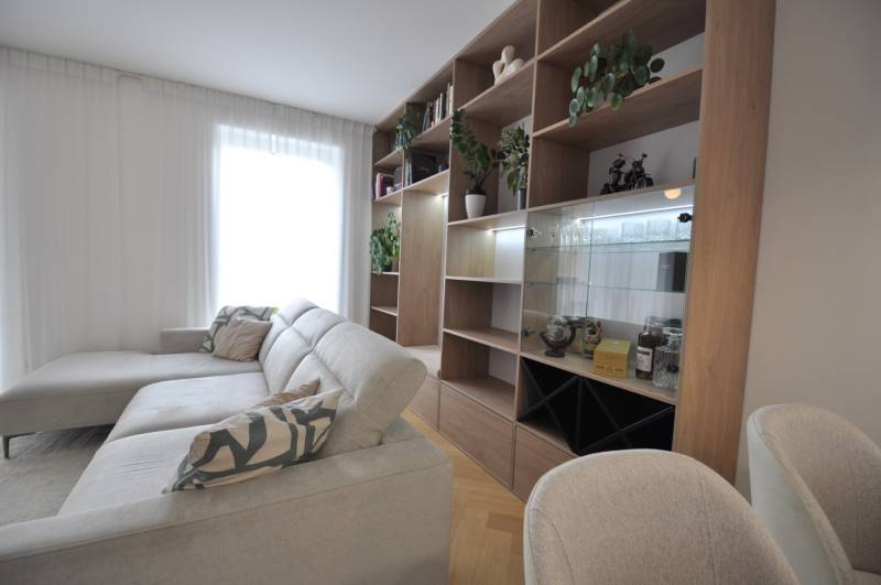 Living room in a family house with a white couch, wooden bookshelf, and plants.
