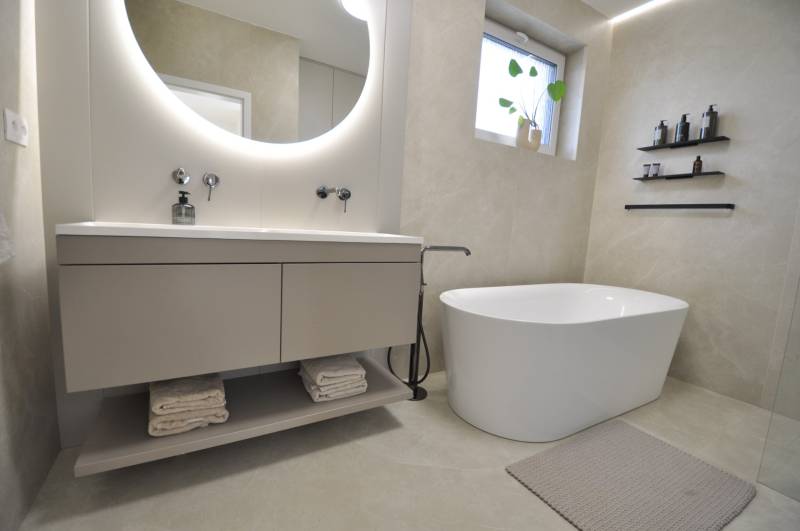A bathroom in a family house with a freestanding bathtub and a floor with a delicate pattern.