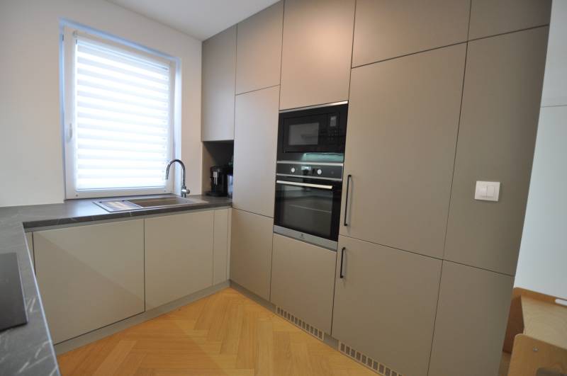 A kitchen in a family house with a wood-patterned floor and built-in appliances.