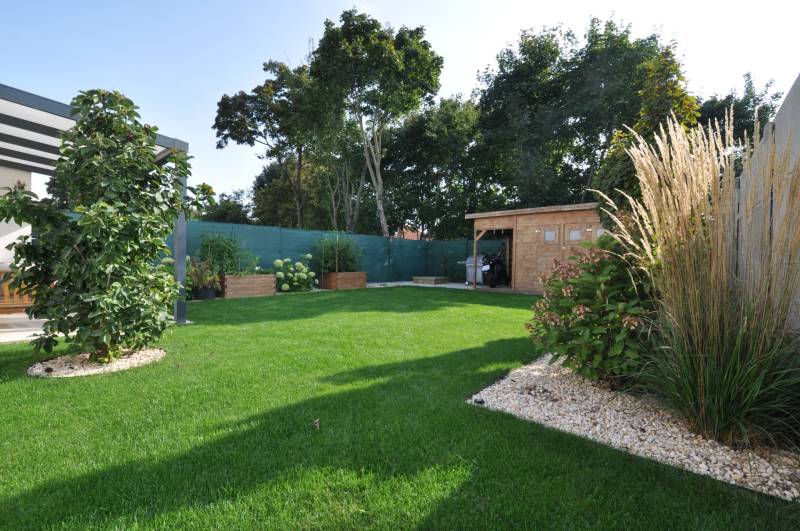 The garden of a family house on Ďuríčkova Street in Miloslavov with a wooden shelter and greenery.