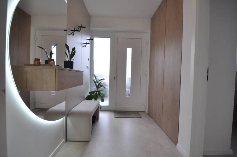 Entrance hall in a family house with a large mirror and storage spaces.