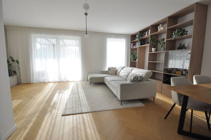 Living room of a family house with a bookshelf, sofa, and wooden decor flooring.