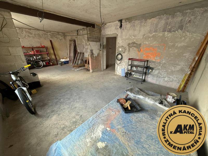 An unfinished room in a family house with a bicycle and shelves for various tools.