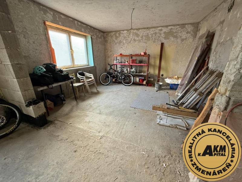 Unplastered room in a family house used as a workshop with stored items and bicycles.