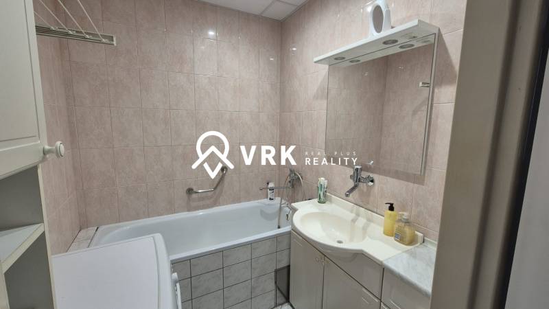 A bathroom with a bathtub, sink, and mirror in a three-room apartment.
