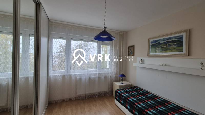 A room in a 3-room apartment with a wooden decor floor and a blue light fixture.