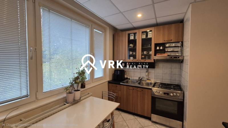 A kitchen in a 3-room apartment with a gas stove, cabinets, and a dining table.