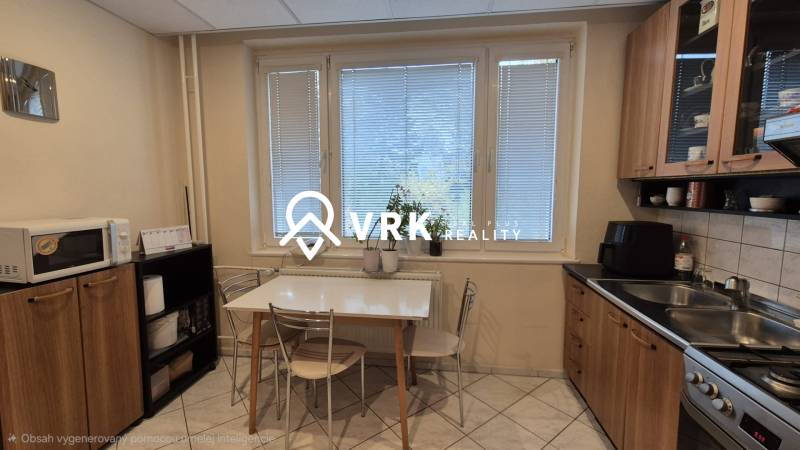 Kitchen of a 3-room apartment with a dining table, kitchen unit, and microwave.
