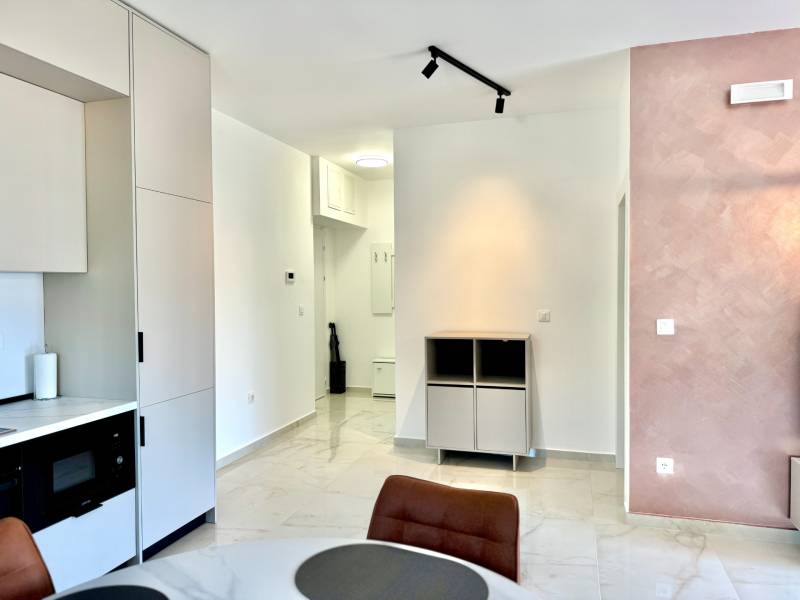 Interior of a 1-room apartment with a kitchen unit, dining table, and light-colored walls.