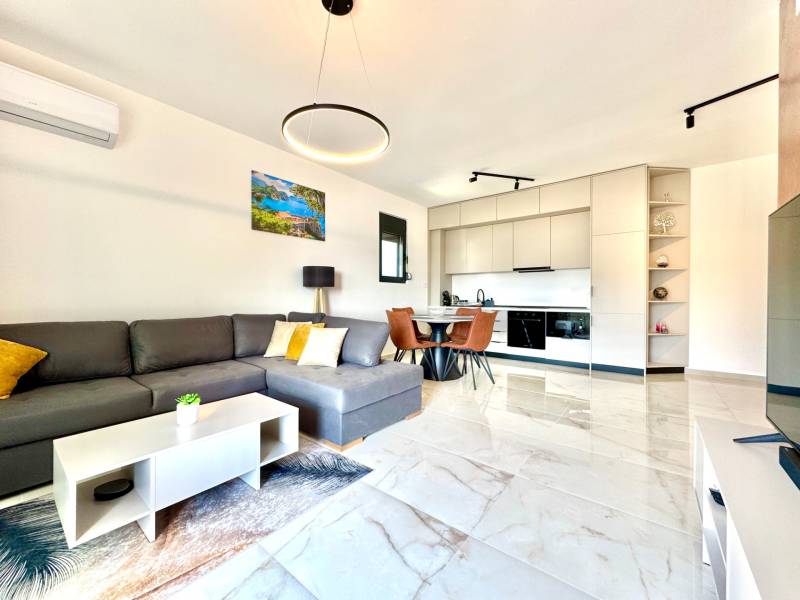 Interior of a 1-room apartment with a sofa, kitchenette, and dining table.