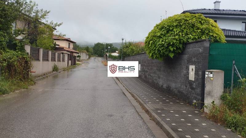 A rainy alley in Limbach surrounded by properties - residential, with fences and greenery.