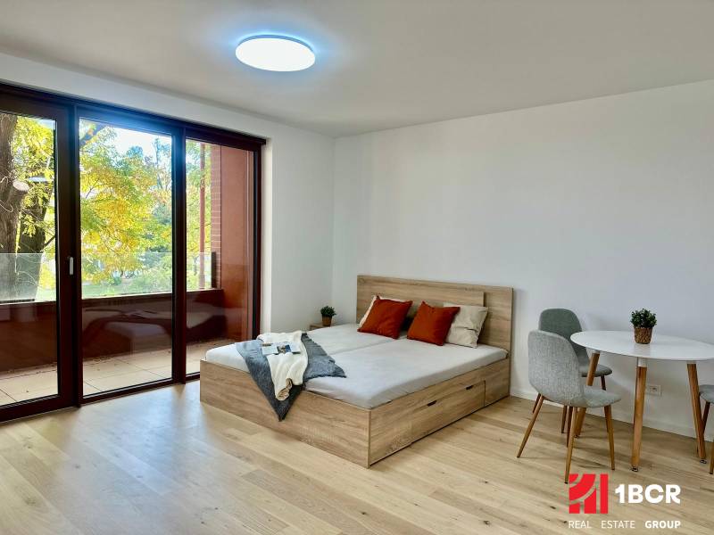 1-bedroom apartment with a bed, table, and floor with a wood decor.