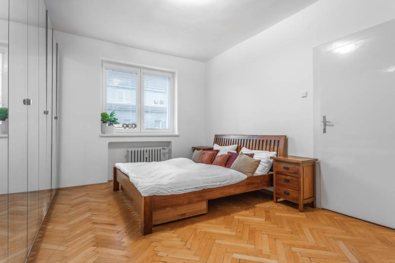 A bedroom in a 3-room apartment with wooden furniture and a wooden decor floor.