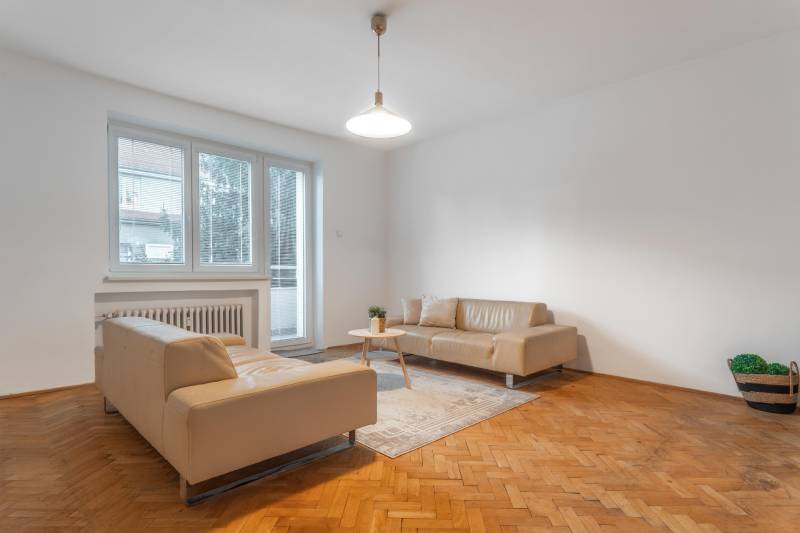 Living room in a three-room apartment with beige sofas and a wooden decor floor.