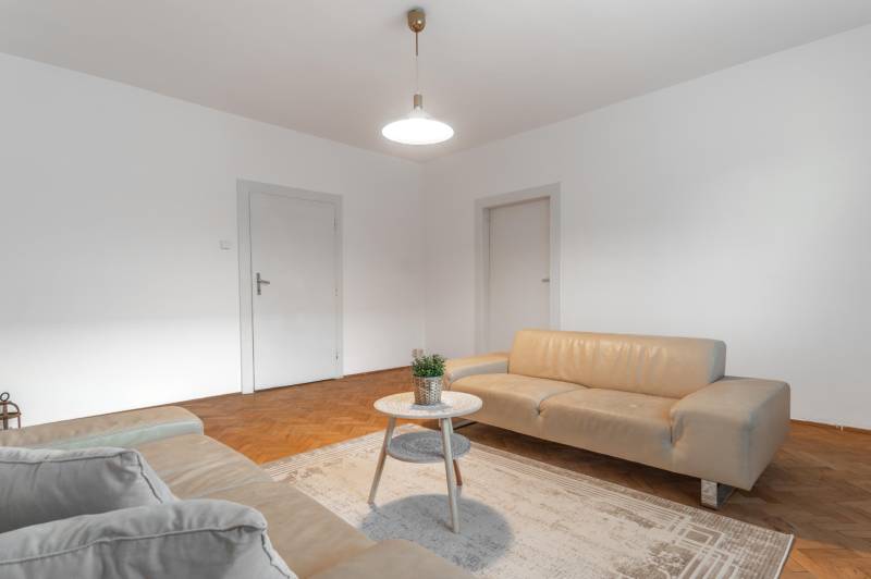 Living room in a three-room apartment with light sofas and a wooden decor floor.