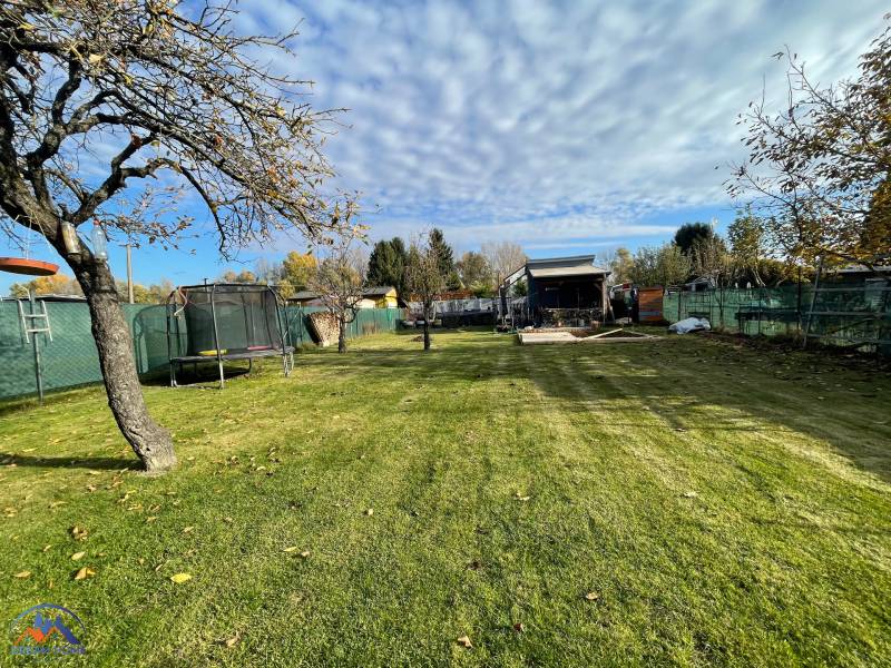 A trampoline in the garden of the Cottage at Nová osada in Komárno with an apple tree and a blue sky.