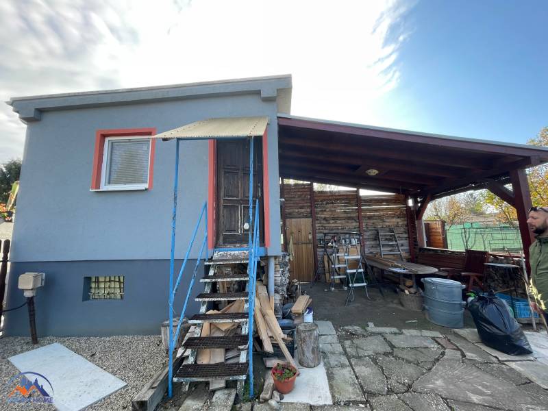 A cottage in Komárno on Nová Osada Street with a covered terrace and wooden staircase.