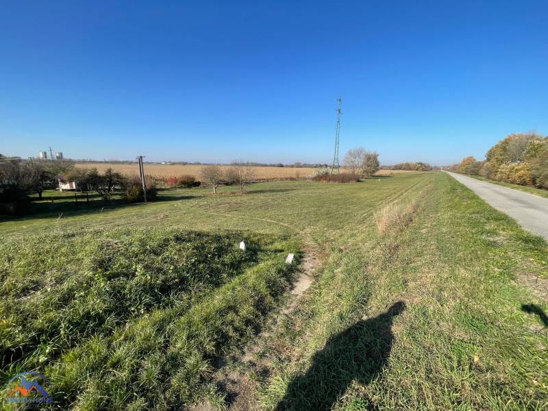 The landscape around the cottage on Nová osada street in Komárno with a field and a road.