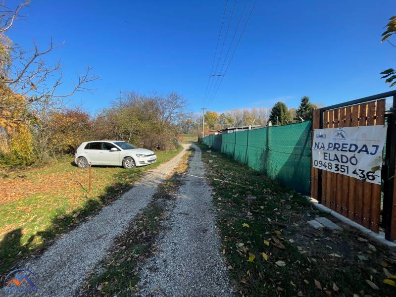 The path to the cottage in Nova Osada in Komárno, next to a parked white car.