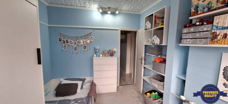 Children's room in a 3-room apartment with blue walls, shelves, and light furniture.
