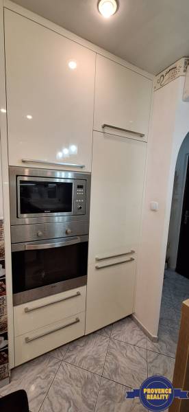 A kitchen in a 3-room apartment with white cabinets and built-in appliances.