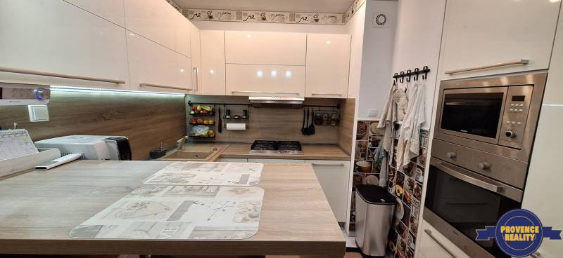 A kitchen in a 3-room apartment with a wooden decor floor, modern appliances.