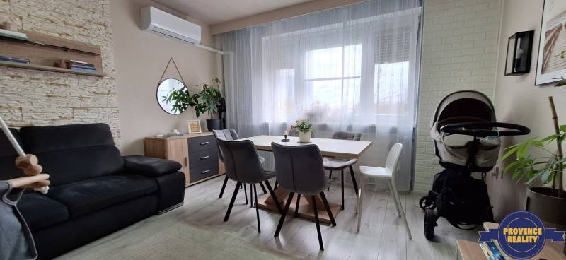 Living room with a gray sofa, wood-decor table, and light curtains in a 3-room apartment.