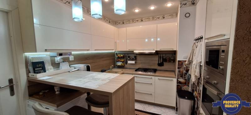 Compact kitchen in a 3-room apartment with white cabinets and wooden decor.
