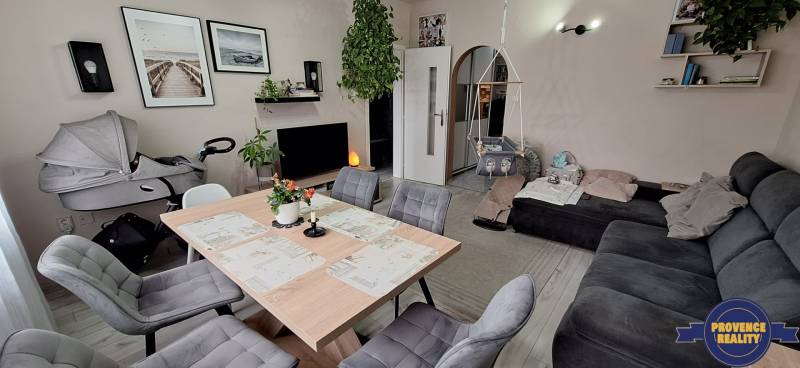 Living room of a three-room apartment with a sofa, table, chairs, and a children's swing.