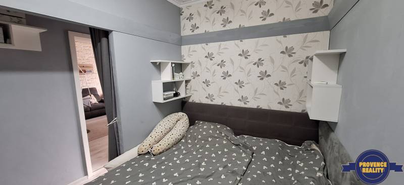 Bedroom in a 3-room apartment with a floral pattern on the wallpaper and gray walls.