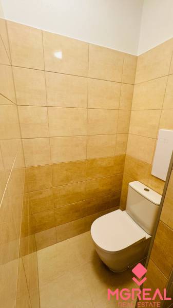 A toilet with beige tiles in a studio apartment.