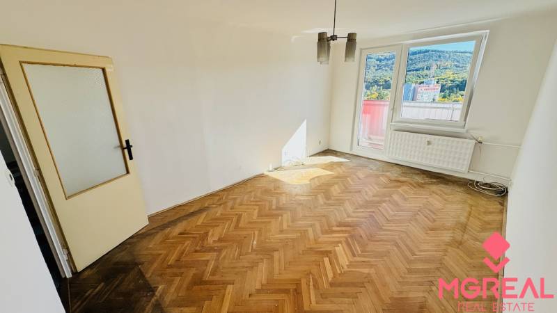 A room with a wooden decor floor in a studio apartment, large window, door with glazing.