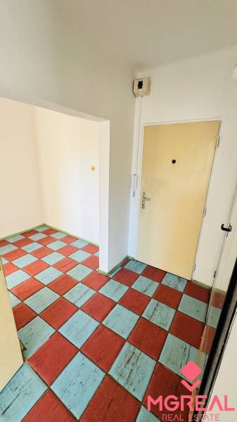 A hallway in a one-room apartment with colorful tiles and light walls.