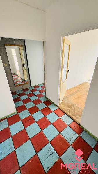 A hallway in a one-room apartment with a colorful floor and a large mirror.