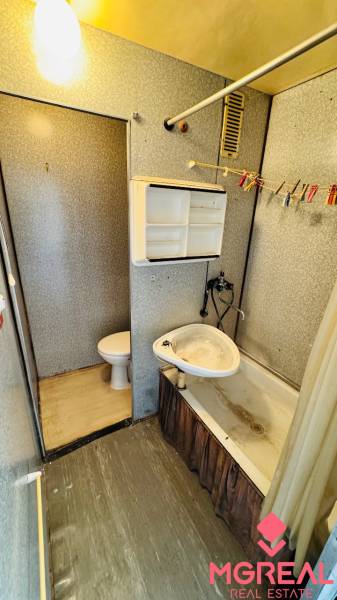 A bathroom in a studio apartment with a bathtub, sink, and separate toilet.