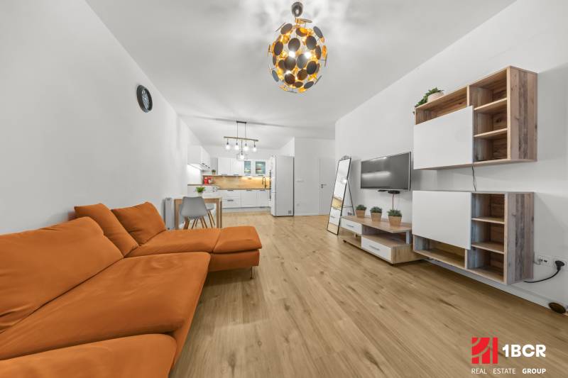 Living room with an orange sofa and a wooden decor floor in a two-room apartment.