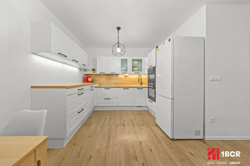 A kitchen in a 2-room apartment with white cabinets and a wood-patterned floor.