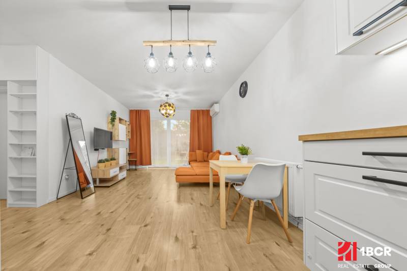 Living room in a 2-room apartment with a wooden decor floor and orange furniture.