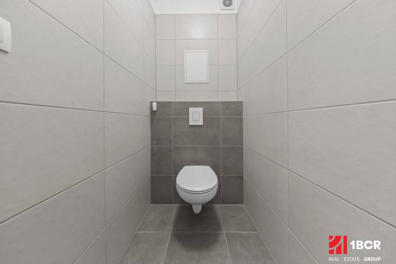 A toilet with tiles in a 2-room apartment, simple design and neutral colors.