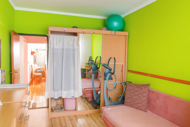 A striking green wall and a mirrored wardrobe in a 2-room apartment. In the background, a stationary bike.
