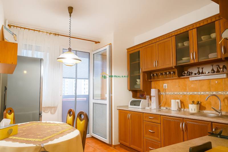 A kitchen in a 2-room apartment with wooden cabinets, a dining table, and access to a balcony.