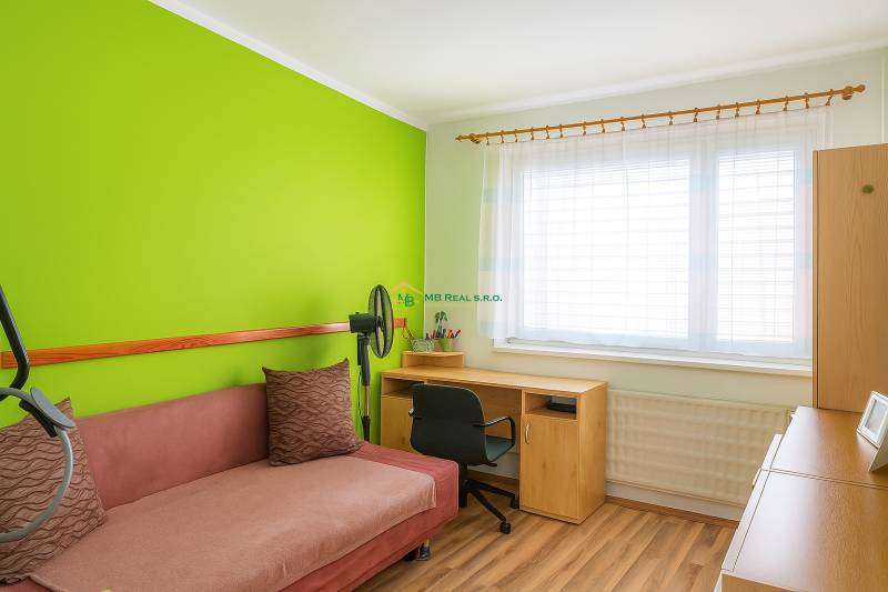 A room with a colored wall, a sofa, a table, and a wooden decor floor in a 2-room apartment.
