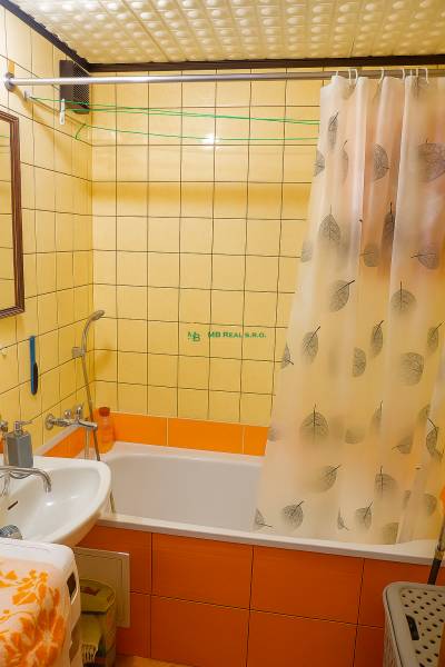 Bathroom in a 2-room apartment with a bathtub, shower curtain, and tiles.