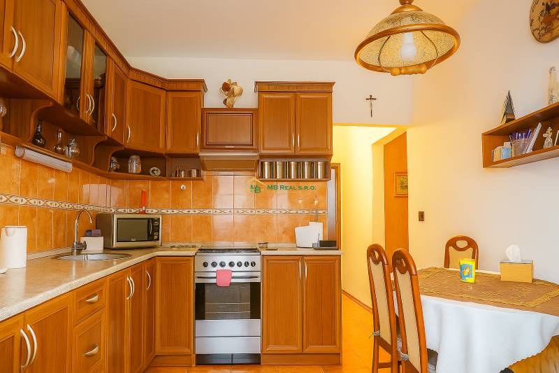 A kitchen in a 2-room apartment with wooden cabinets and a dining table.