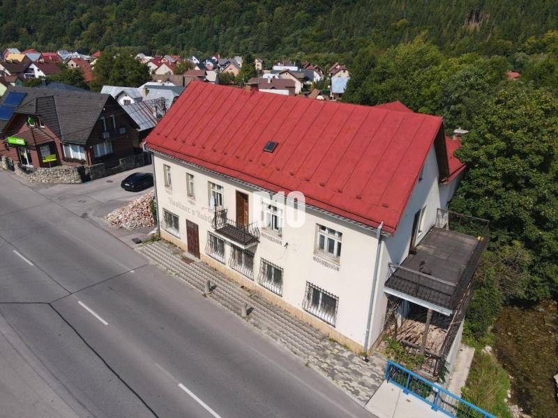 A building in Belá with a red roof, surrounding houses and nature.
