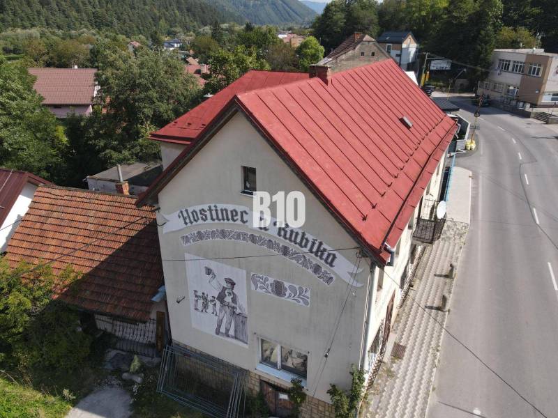 The building of the inn in Belá with a red roof and a depiction on the wall.