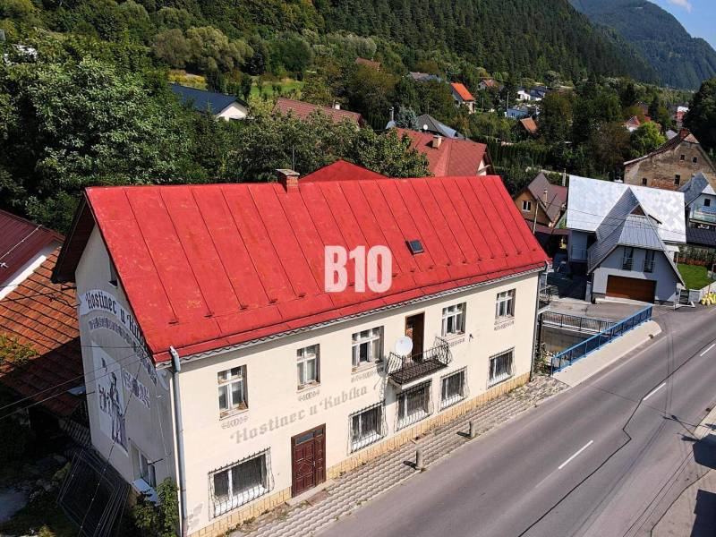 A building in Belá with a red roof on the main street surrounded by greenery and houses.