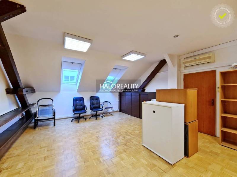 Offices with wood-patterned flooring, chairs, and windows in an attic room.