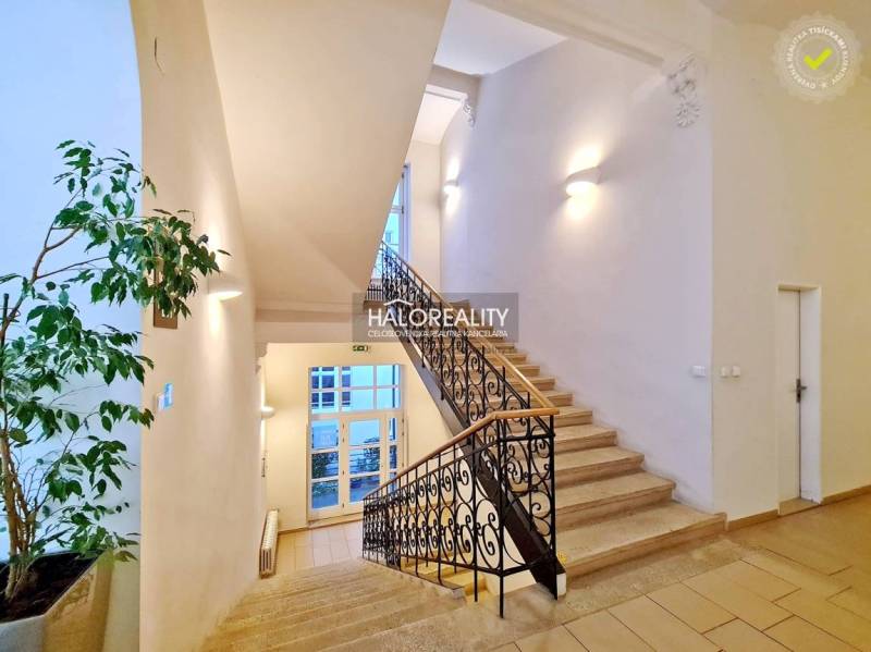 A bright staircase with decorative railings leading to offices.