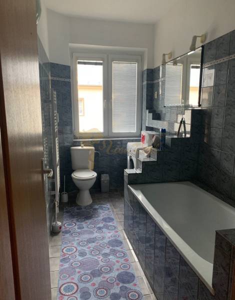 A bathroom in a 2-room apartment with blue tiles, a bathtub, and a sink.